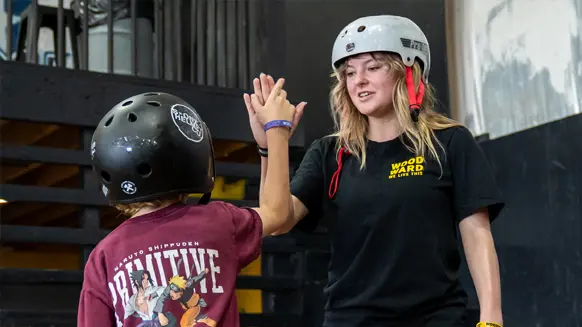 skate camper and instructor high-fiving